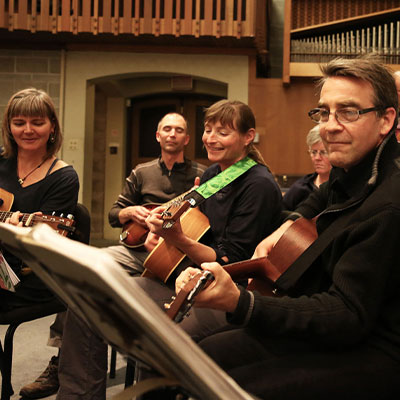 Adults playing guitars in a group class 400px