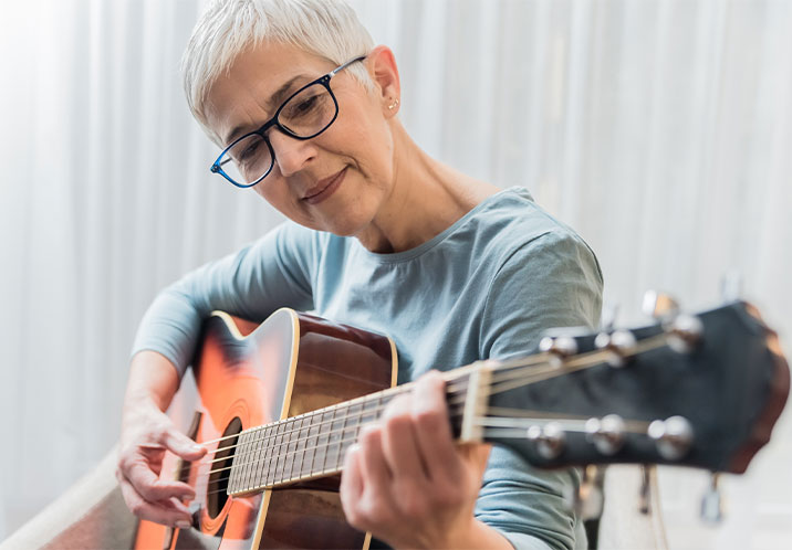 Older woman playing guitar 716x498px