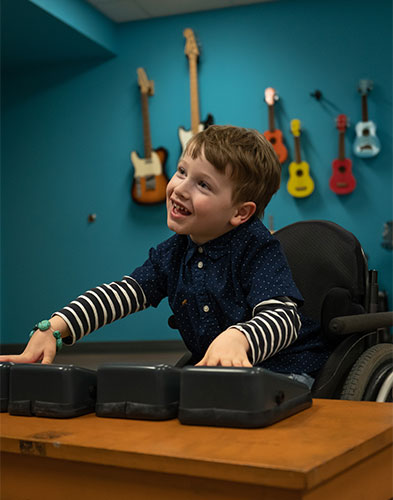 Young male Music Therapy client in a wheelchair playing music