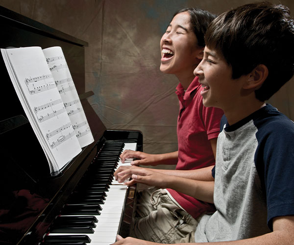 Two students laughing at a piano