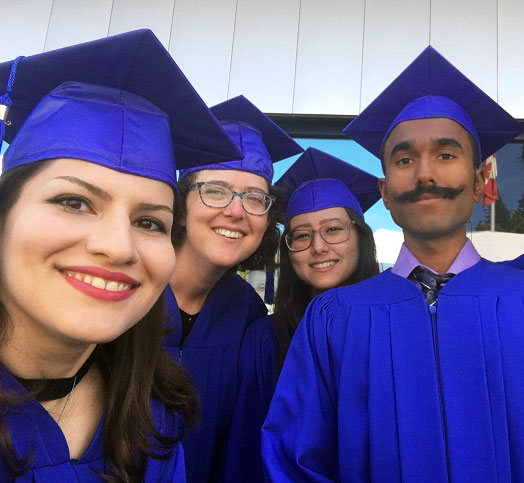 Four postsecondary graduates wearing bluehats and robes