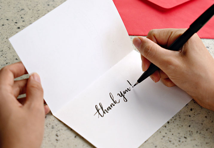 Hands writing a thank you note 716x498px