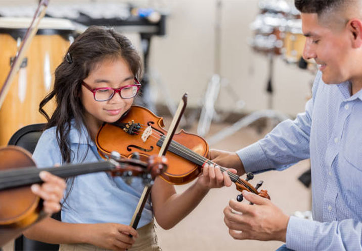 Teacher helping young girl play the violin landscape