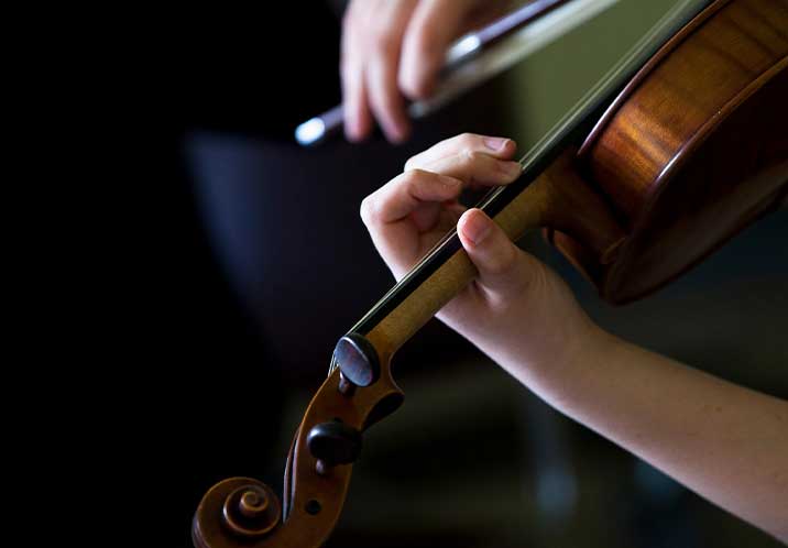 Hands playing a violin 716x498px