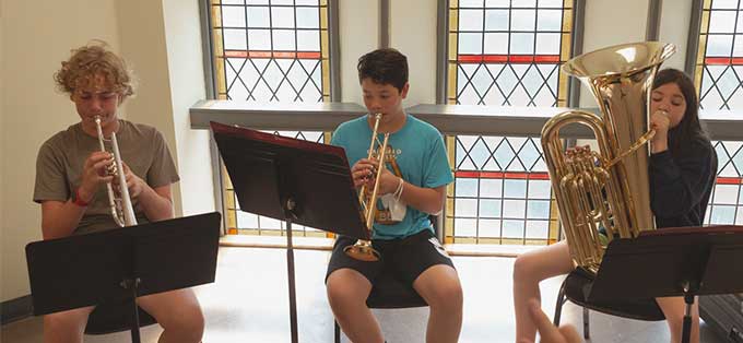 Teenage brass students playing trumpets and tuba