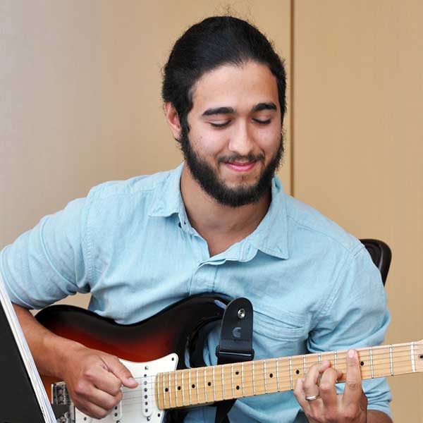Male postsecondary student playing electric guitar