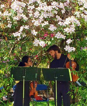 Garden Tour two student musicians talk underneath a pergola of flowers