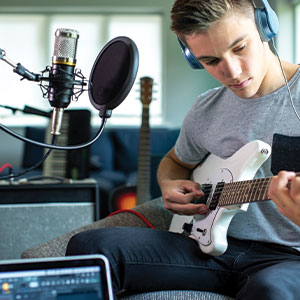 Young man with guitar and recording equipment in his living room