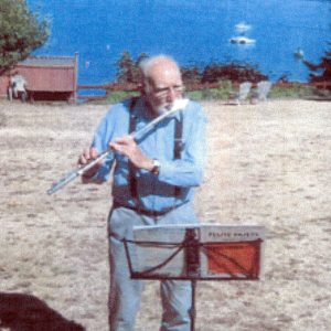 Tom Underwood playing the flute on a beach