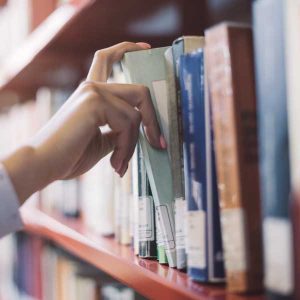 Hand removing library book from a shelf 600px