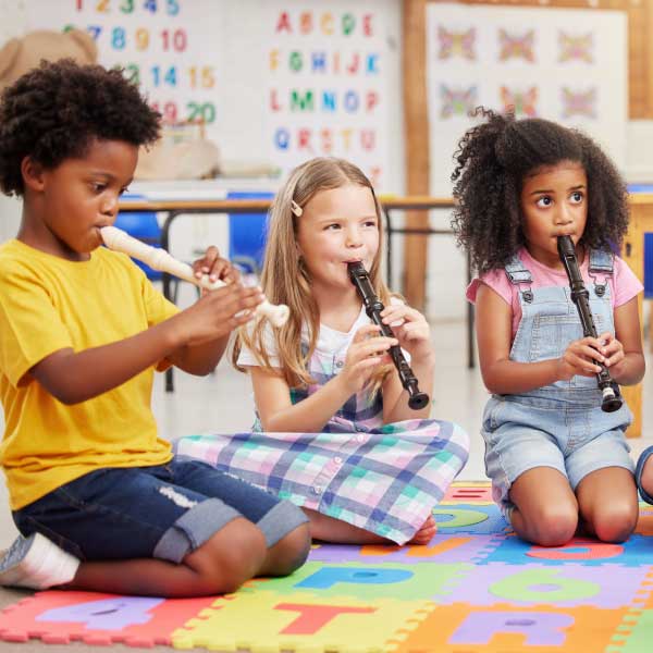 Three children play the recorder in a group class
