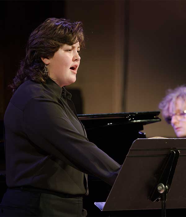 Postsecondary sings on stage with pianist